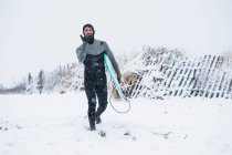Man going surfing during winter snow — Stock Photo