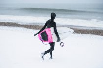 Woman surfing during winter snow, South Kingstown, RI, Estados Unidos - foto de stock