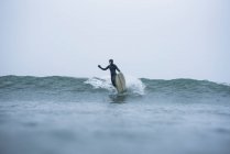 Woman surfing during winter snow, South Kingstown, RI, United States — Stock Photo