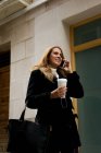 Young woman talks on her phone while walking down the street — Stock Photo