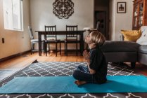 Jeune garçon faisant du yoga dans le salon pendant l'isolement — Photo de stock