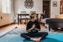Jovem fazendo ioga na sala de estar durante o isolamento — Fotografia de Stock