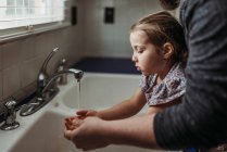 Menina lavar as mãos na pia do banheiro com sabão. — Fotografia de Stock