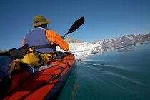 Hombre viajando en un kayak de mar a través de los fiordos del este de Groenlandia - foto de stock