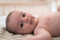 Gros plan portrait de bébé garçon couché sur le lit à la maison — Photo de stock