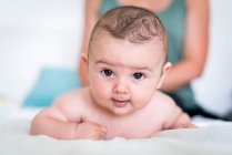 Close-up portrait of cute baby boy with brown eyes lying on bed — Stock Photo