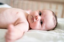 Portrait de bébé garçon torse nu mignon couché sur le lit à la maison — Photo de stock