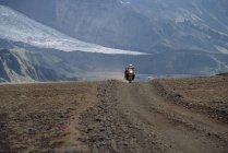 Людина їде на своєму пригодницькому мотоциклі по гравіюююююююювальній дорозі в Ісландії — стокове фото