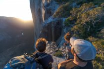 Três caminhantes olhando para o The Nose El Capitan de cima ao pôr do sol — Fotografia de Stock