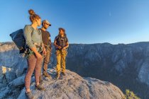 Three hikers at the top of El Capitan in Yosemite Valley at sunset — Stock Photo