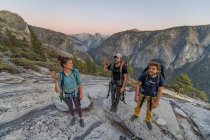 Three hikers at the top of El Capitan in Yosemite Valley at sunset — Stock Photo