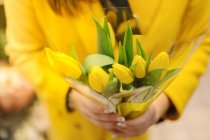 Eine unkenntliche Frau mit einem Strauß gelber Tulpen. Sie erhält gerade — Stockfoto
