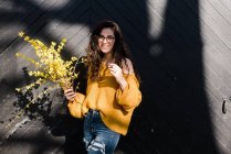 Young woman holding forsythia in pretty sunlight — Stock Photo