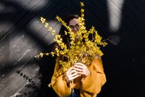 Young woman holding forsythia in the sunshine — Stock Photo