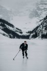 Jovem em um terno jogando hóquei no inverno gelo congelado — Fotografia de Stock