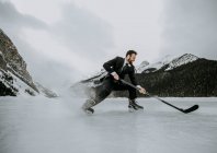 Молодий чоловік у костюмі грає в хокей взимку заморожений лід — стокове фото