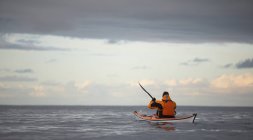 Взрослый человек, управляющий своим морским каяком через спокойные воды вокруг Рейкьявика — стоковое фото