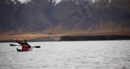 Hombre maduro dirigiendo su kayak de mar a través de aguas tranquilas alrededor de Reykjavik - foto de stock