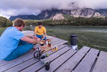 Paar sitzt auf Bank und trinkt Kaffee am See — Stockfoto