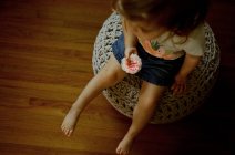 Junges Mädchen sitzt auf einem Windbeutel und hält eine rosa Blume in ihrem Wohnzimmer — Stockfoto