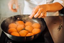 Chef cooking fried apricots in a frying pan on background, close up — Stock Photo