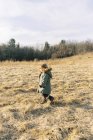 Little girl walking through a field in the wintery evening sun. — Stock Photo