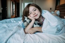 Little girl lying on bed in the bedroom — Stock Photo