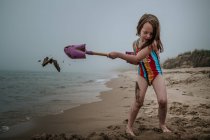 Kleines Mädchen spielt mit einem Spielzeugboot am Strand — Stockfoto