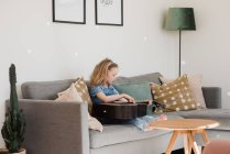 Jeune fille assis à la maison jouer de sa guitare — Photo de stock