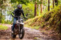 Чоловік їде своїм мотоциклом типу скремблера через ліс — стокове фото