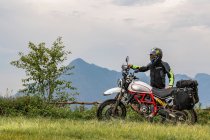 Homem de pé ao lado de sua motocicleta tipo scrambler — Fotografia de Stock