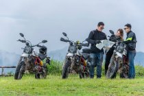 Trois amis regardant la carte sur le voyage à moto — Photo de stock