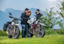 Three friends looking at map on motorcycle trip — Stock Photo