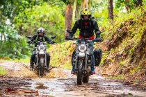Two friends riding their scrambler motorcycles through forrest — Stock Photo