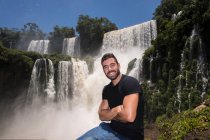 Junger Mann posiert vor den Wasserfällen von Iguacu in Argentinien — Stockfoto