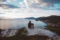 Randonneur assis sur un rocher regardant la mer et les îles — Photo de stock