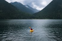 Personne en kayak pagayant sur le lac vers les montagnes — Photo de stock