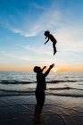 Dad throws his toddler daughter into the air at florida beach sunset — Stock Photo