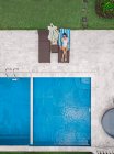 Luftaufnahme einer Frau, die sich am Wochenende am Pool entspannt — Stockfoto