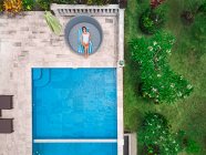 Vue aérienne supérieure de la femme se détendre autour de la piscine pendant le week-end — Photo de stock