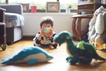 Un niño toma fotos de sus juguetes con su cámara - foto de stock