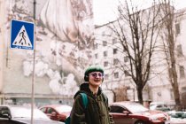 Portrait of happy hipster listening music in headphones walking in city — Stock Photo