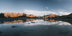 Panorama of a young woman standing in front of a puddle, Canterbury, New Zealand. — Stock Photo