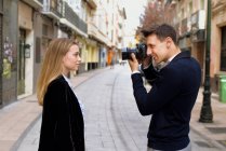 Young man photographs his friend on the street of a European city — Stock Photo