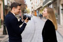 Joven fotografía a su amigo en la calle de una ciudad europea - foto de stock