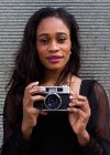 Head portrait of a young African-American woman posing with a camera — Stock Photo
