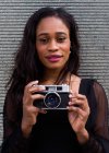 Retrato de una joven afroamericana posando con una cámara - foto de stock