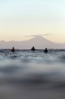 Surfeurs en planche de surf sur la mer attendant une vague, Volcan Rinjani — Photo de stock