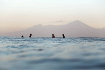 Серфингисты на доске для серфинга в море ждут волну, вулкан — стоковое фото