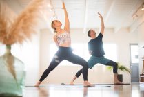 A couple in Reverse Warrior pose during yoga. — Stock Photo